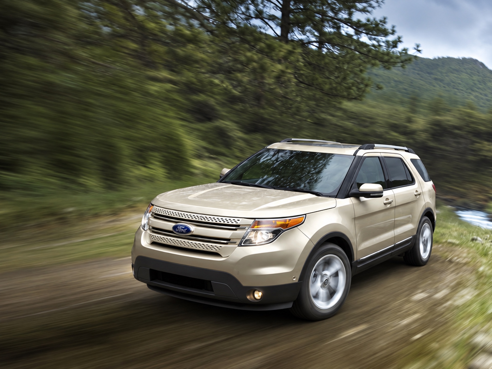 Redesigned 2011 Ford Explorer driving quickly along a forest road