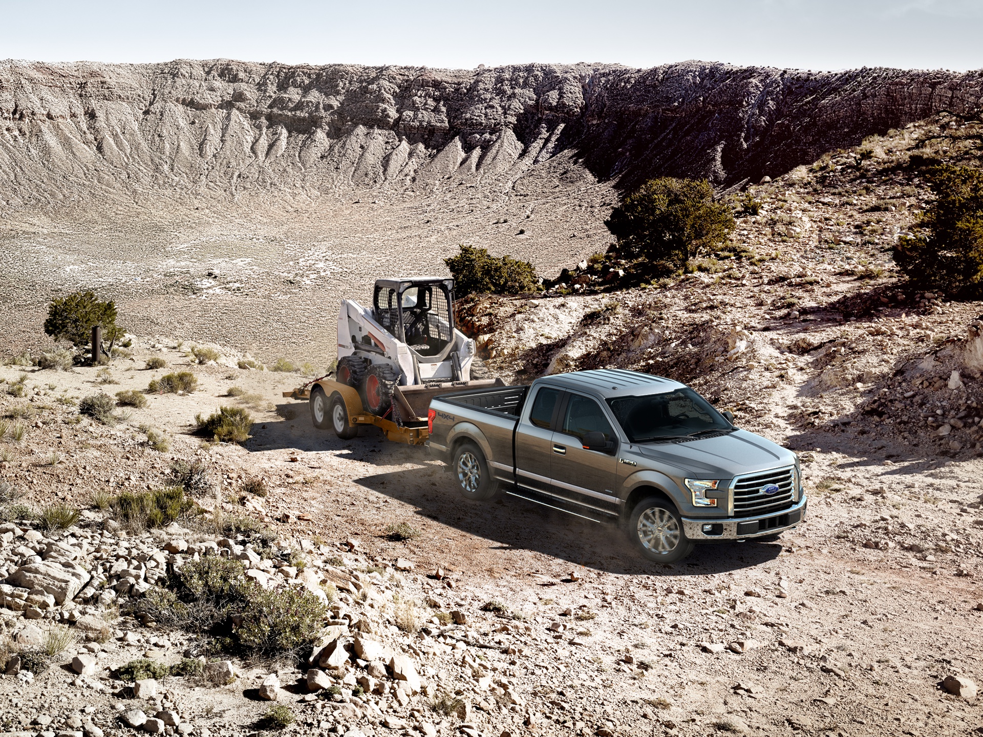 Ford F-150 towing construction equipment through a rugged desert quarry