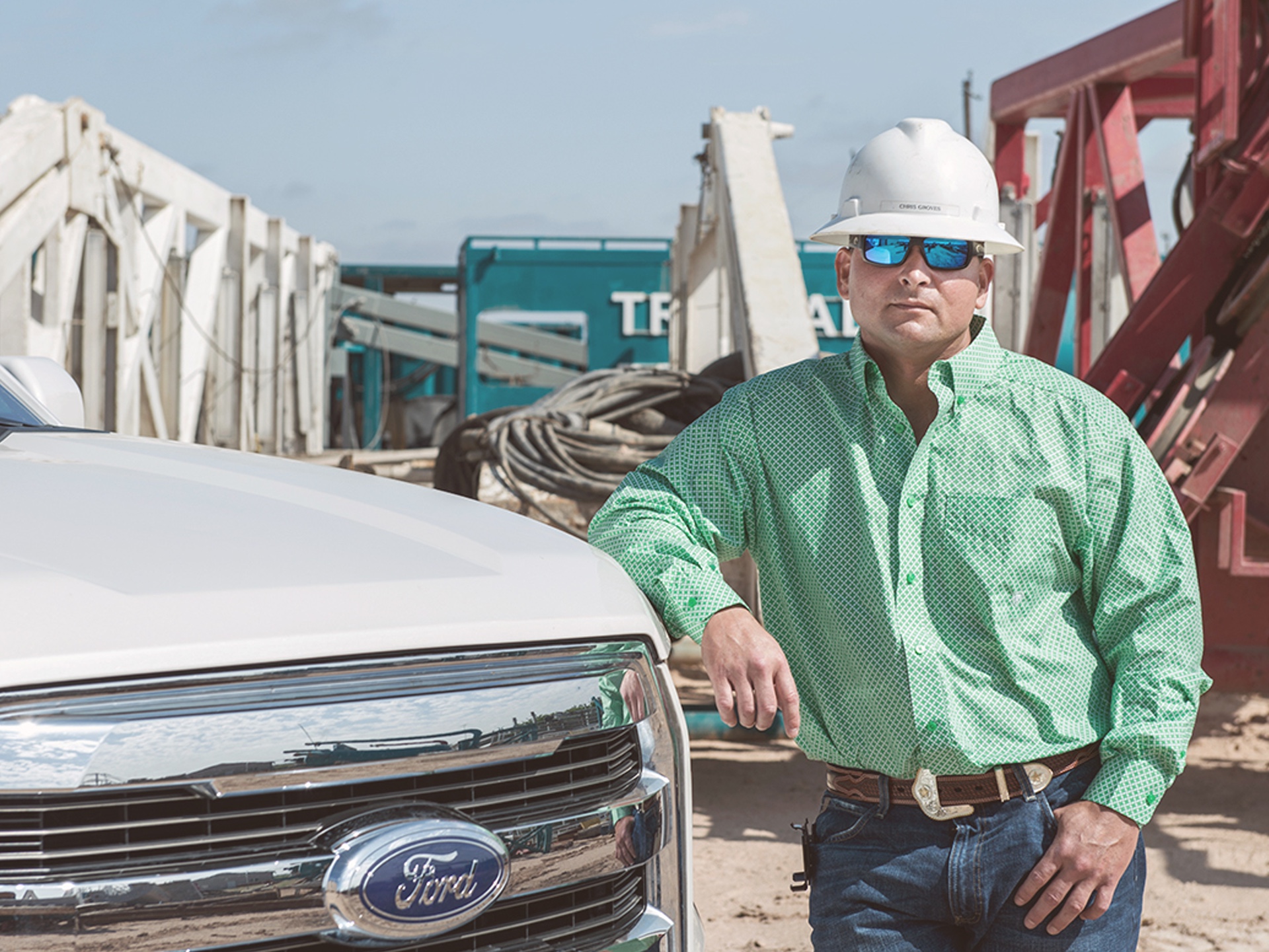 F-150 owner Chris Groves standing beside his white Ford truck at an industrial worksite