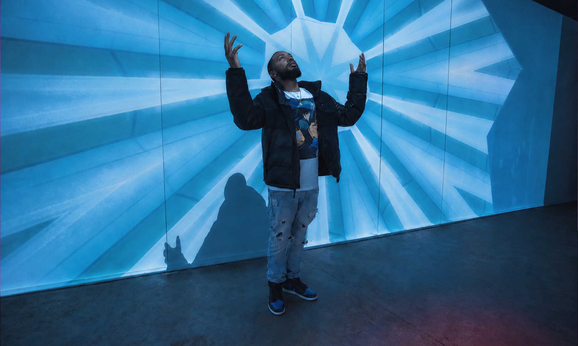 Visitor standing before a radiant blue geometric projection inside Spacecraft
